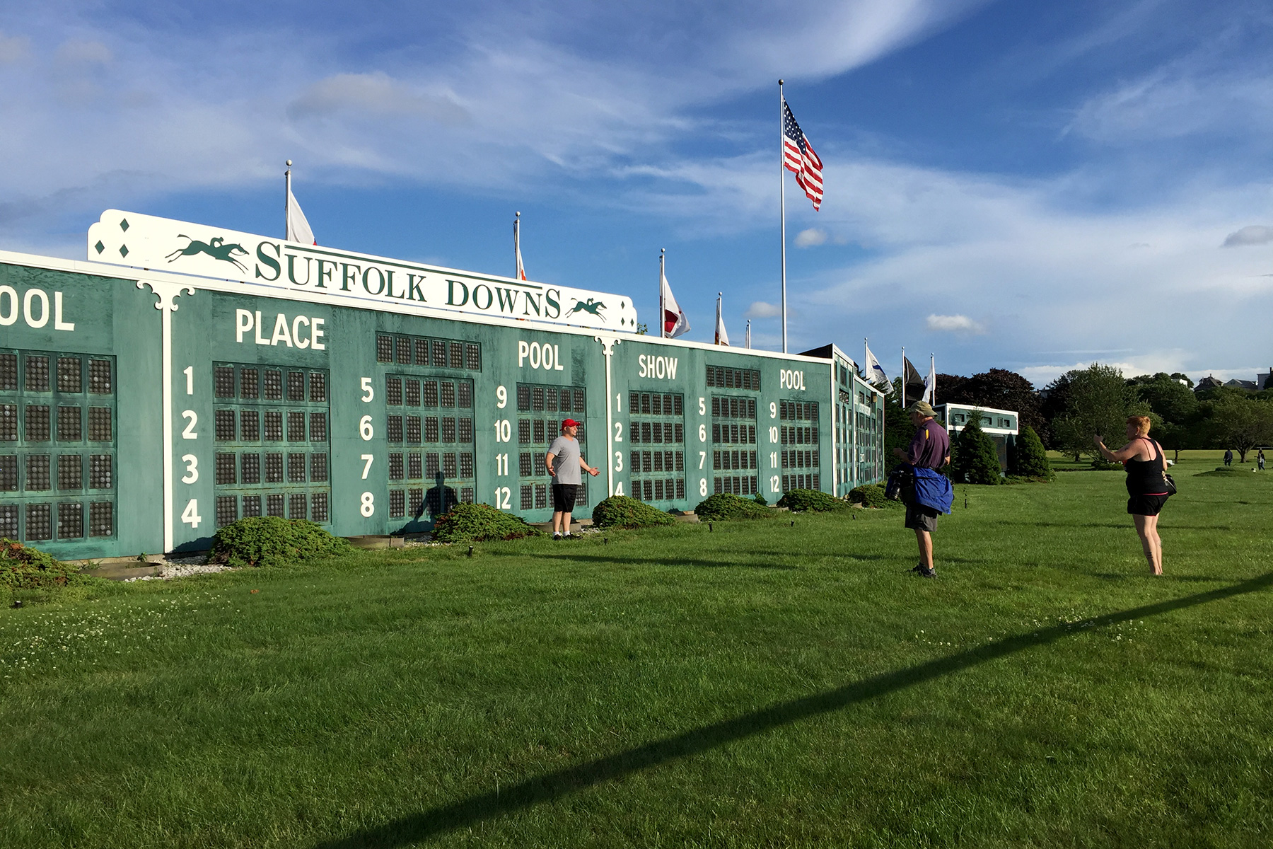 People cross the track to take their photos in front of the infield tote board